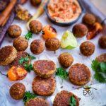 Falafel burger patties and roundels on a plate with humus and other accompaniments