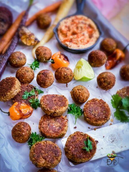 Falafel burger patties and roundels on a plate with humus and other accompaniments